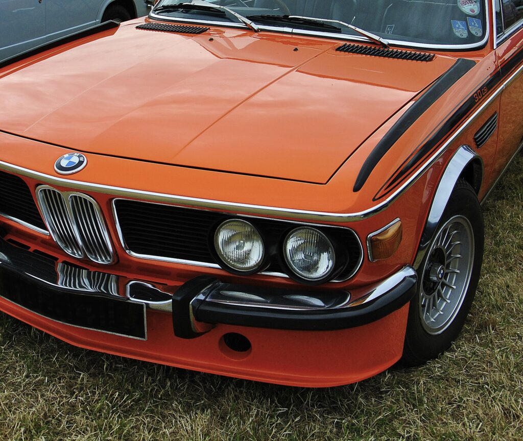Retro Orange BMW Wallpaper: Classic Car Nostalgia with Grassy Background