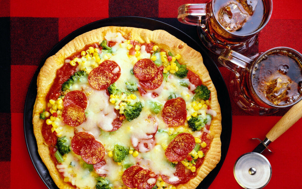 Retro pepperoni pizza with broccoli corn melted cheese on black plate red checkered tablecloth Wallpaper