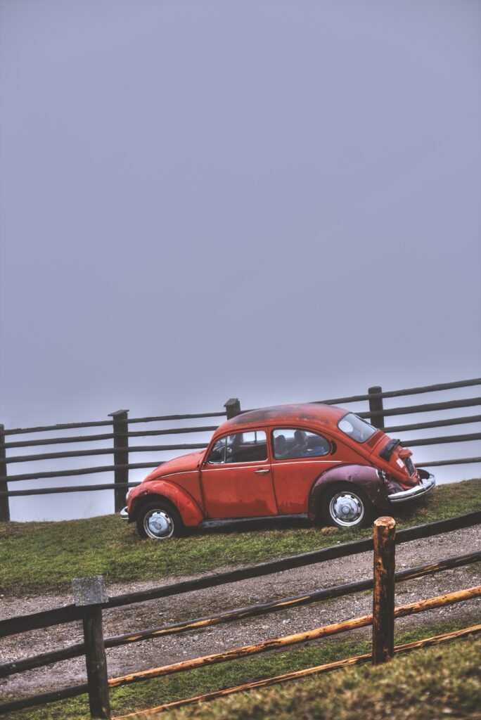 Retro Red Car on Grassy Hillock - Foggy Serene Background Wallpaper