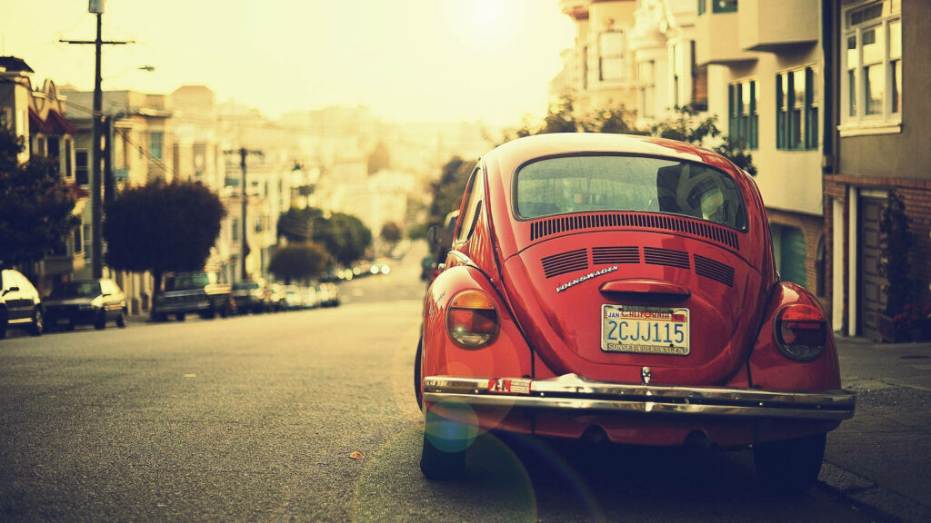 Retro Charm: Sepia-Toned Vintage Volkswagen On City Street Wallpaper