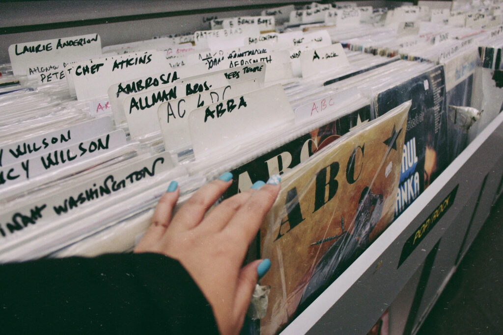 Retro magazine wallpaper with vinyl records and hand reaching ABBA album vintage music vibes
