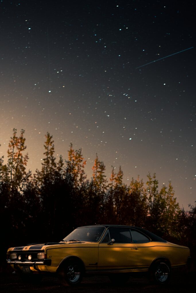Vintage Yellow Car Under Starry Night Sky Wallpaper Background