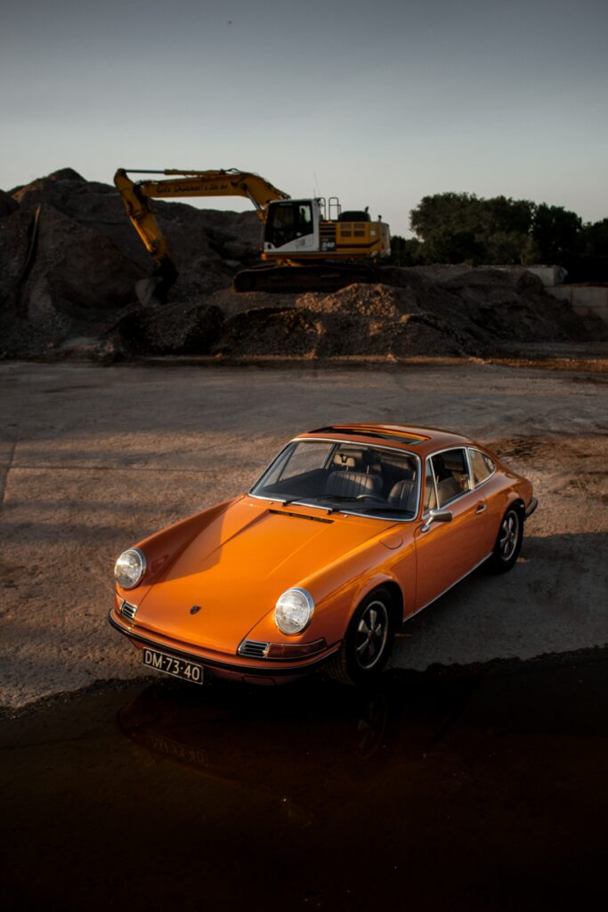 Classic Yellow Porsche Wallpaper: Retro Elegance Meets Industrial Backdrop