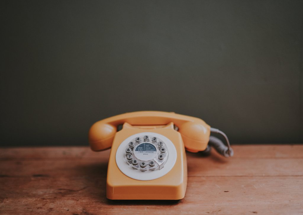 Retro yellow telephone on rustic wood dark wall vintage aesthetic wallpaper background