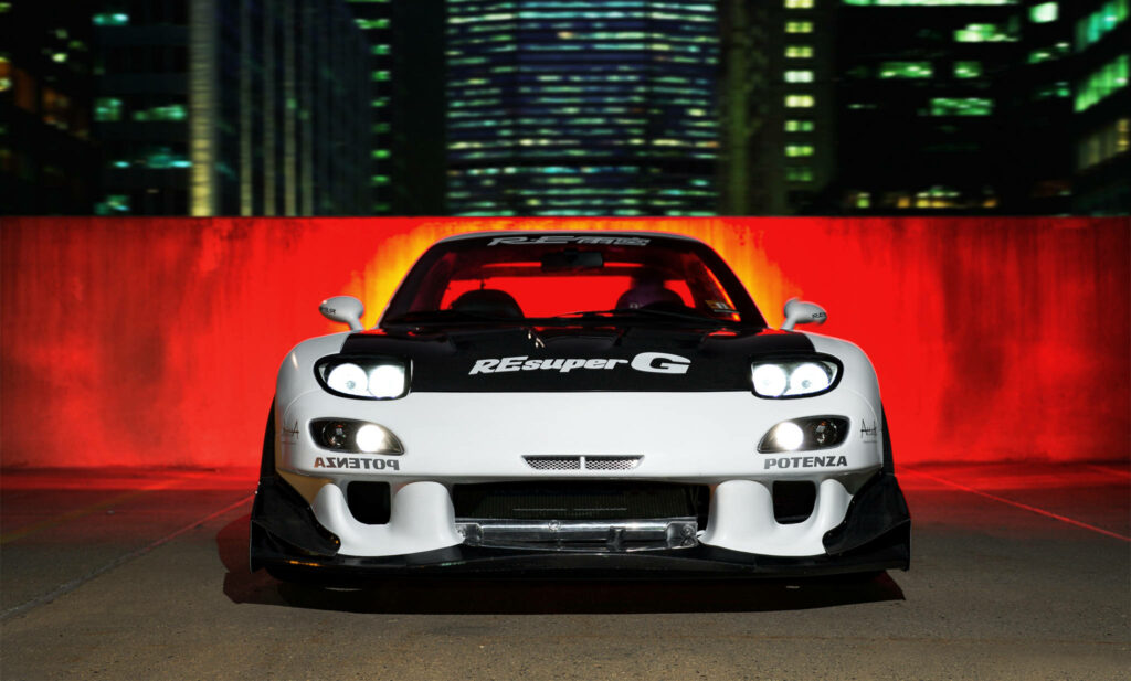 Revved up Mazda RX-7 showcases Resuperg decal against vibrant red backdrop Wallpaper
