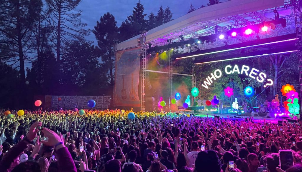 Rex Orange County concert vibrant neon flowers massive crowd WHO CARES screen twilight sky wallpaper