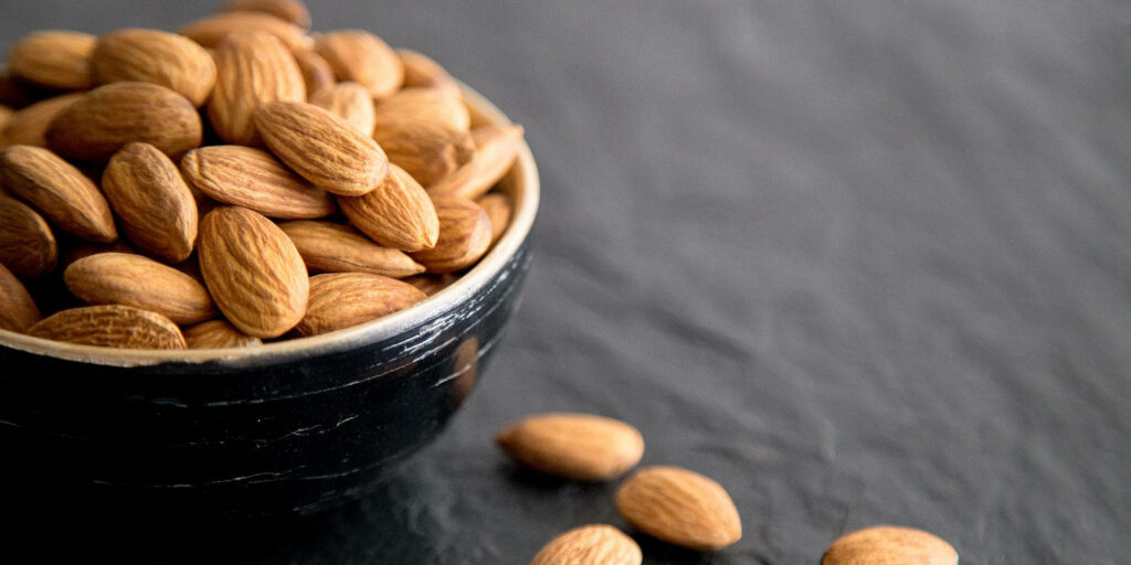 Almond Bowl Close-Up: Natural Texture on Dark Wallpaper Background