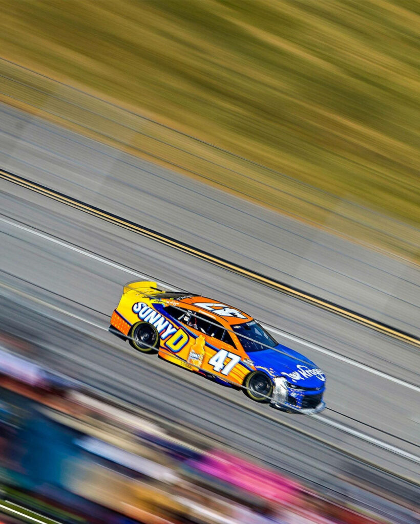Ricky Stenhouse Jr racing SunnyD 47 car speeding on track motion blur background wallpaper