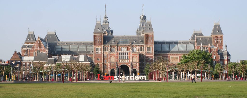 Widescreen view of Rijksmuseum Amsterdam with I amsterdam sign on Museumplein lawn in daylight Wallpaper