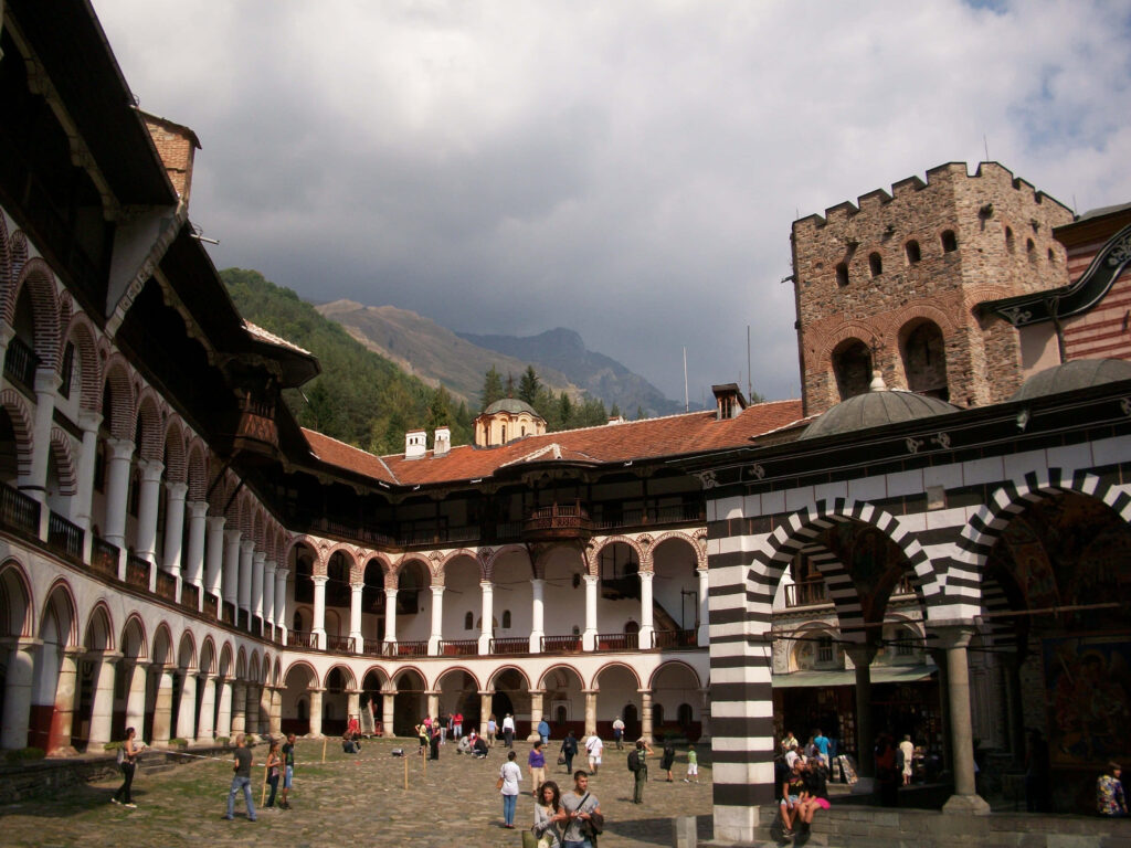 Tourists exploring Rila Monastery Bulgaria historic architecture with scenic mountain backdrop wallpaper