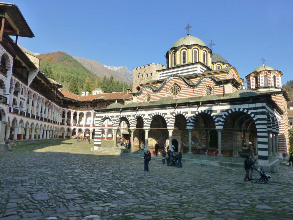 Rila Monastery Bulgaria wallpaper with striped arches domes and scenic mountain background
