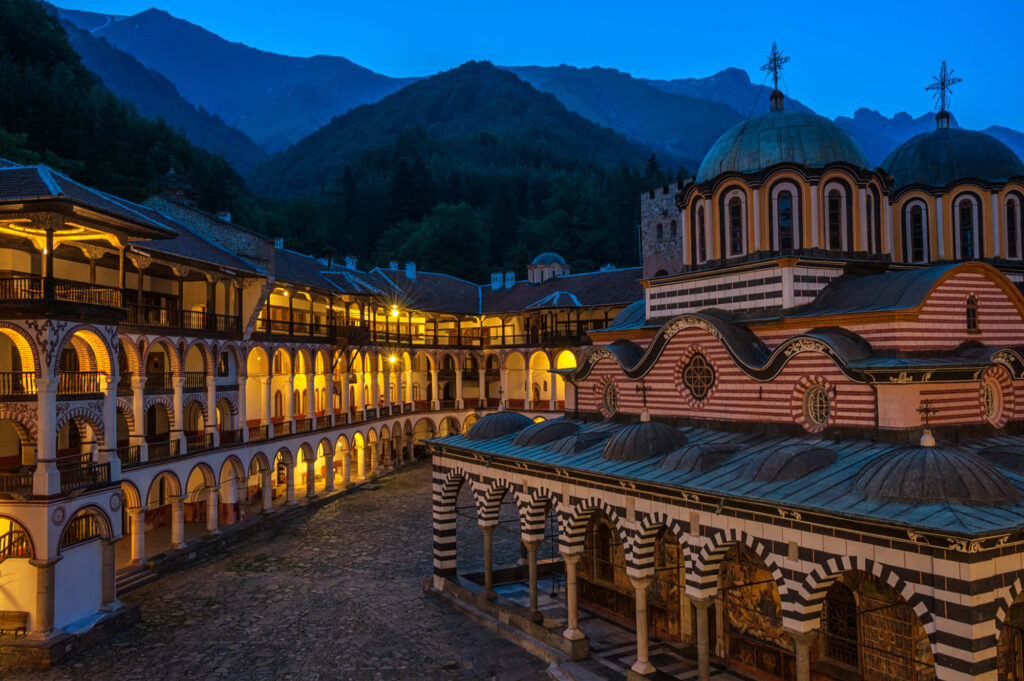 Rila Monastery illuminated at twilight with mountains in Bulgaria nightscape wallpaper background