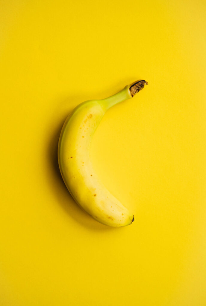Ripe banana on vibrant yellow background minimalist wallpaper bright cheerful fruit image
