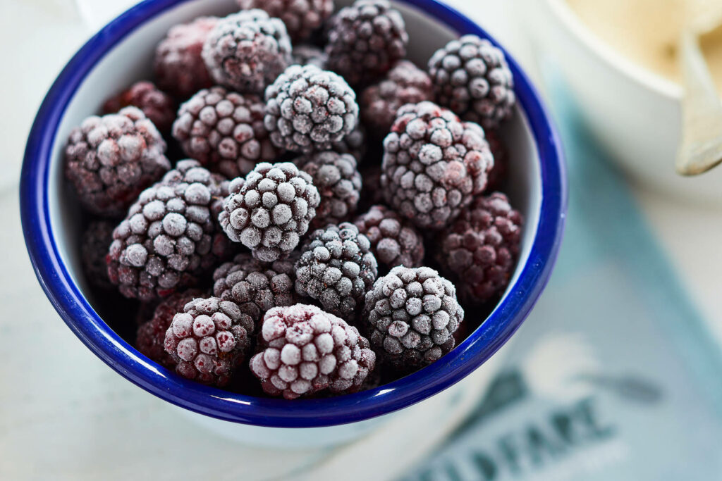 Close-up of frosty ripe boysenberries in white blue bowl detailed purple fruit wallpaper