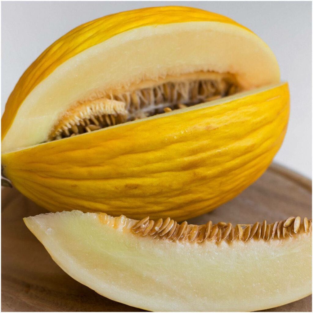 Close-up of ripe Canary melon with yellow rind pale green flesh and shiny seeds wallpaper background