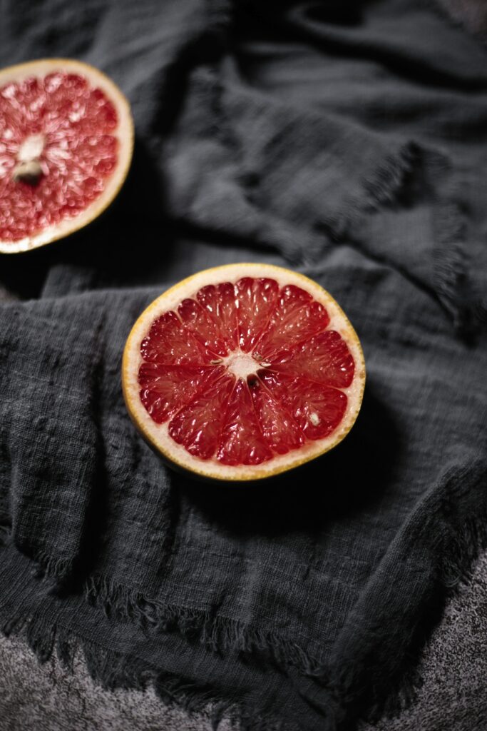 Vibrant Red Grapefruit Close-Up on Dark Cloth Wallpaper Background