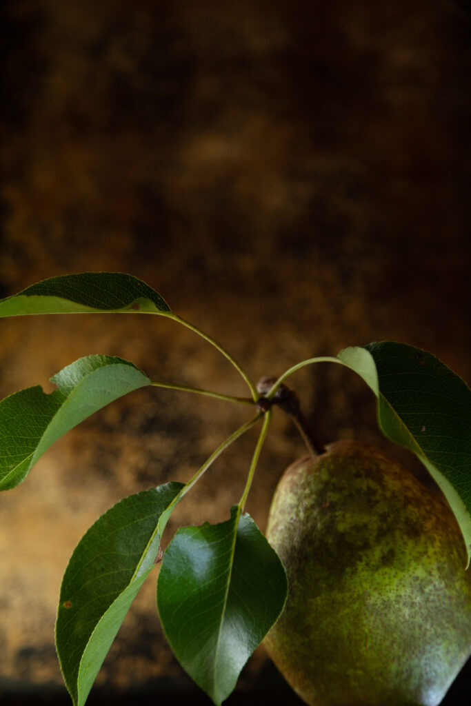 Close-Up Ripe Pear Wallpaper with Green Leaves & Warm Background