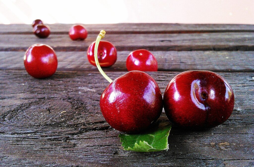 Vibrant Cherry Wallpaper: Glossy Red Cherries on Rustic Wood