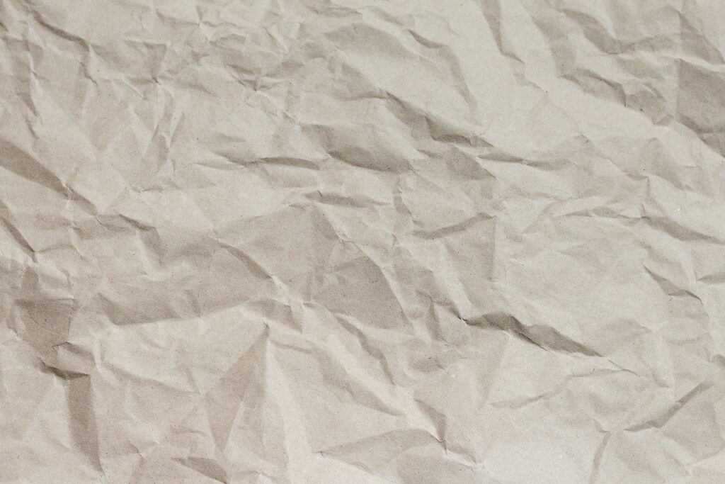 Close-up of crumpled beige kraft paper with natural folds and rustic textured minimalist background Wallpaper