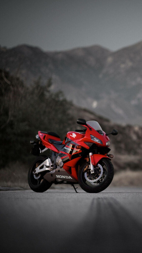 Solitary Journey: Capturing the Thrill of a Honda CBR600RR Motorcycle on a Serene Mountainside Road - Breathtaking Bikes iPhone Background Wallpaper