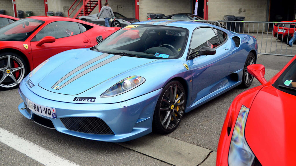 Blue Ferrari F430 Parked Near a Other Ferrari Cars Background Wallpaper
