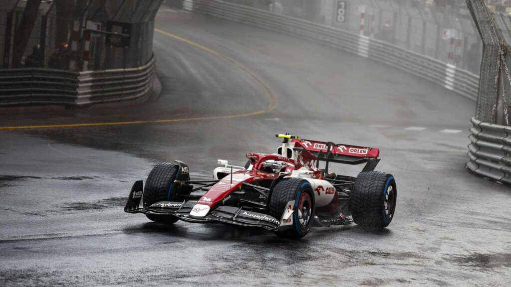 Thrilling Rainy Drive: Guanyu Zhou Maneuvers a Red and White F1 Car Through the Wet Streets of Monaco - Captivating Guanyu Zhou Background Photo Wallpaper
