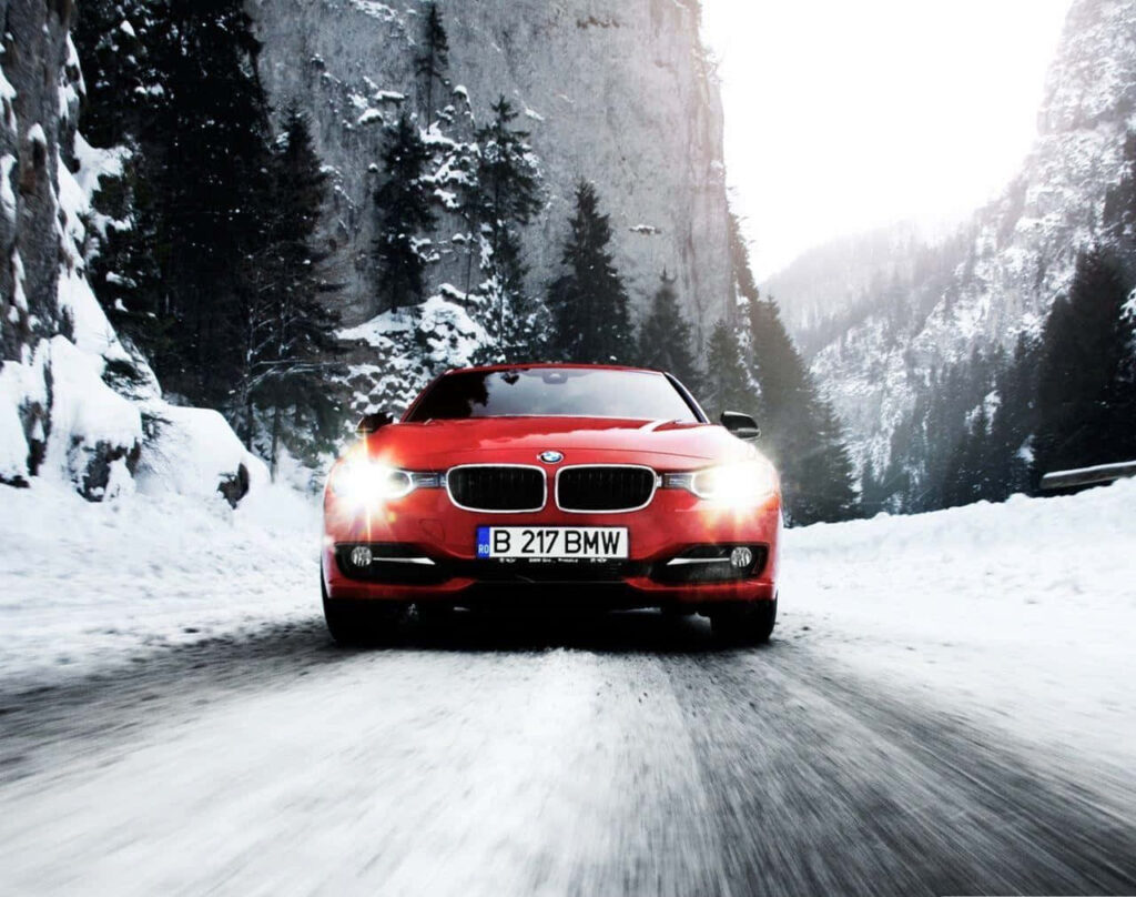 Driving in Winter Wonderland: Breathtaking BMW 320d Model Gliding Along Snowy Trail, Amidst Majestic Trees and Mountains - Captivating BMW Tablet Background Wallpaper
