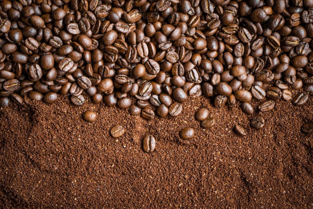 Top-down view of roasted coffee beans on ground coffee background for espresso branding Wallpaper