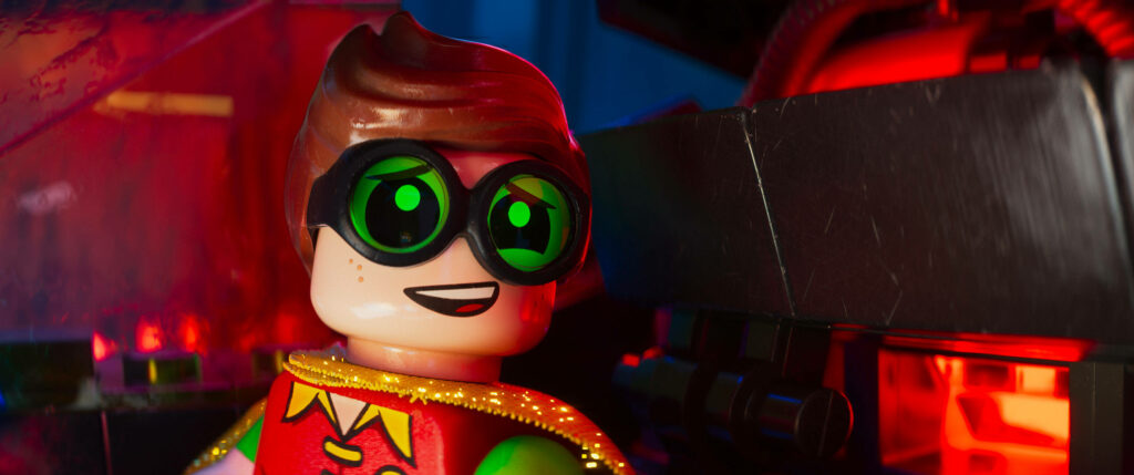 Robin from The Lego Batman Movie smiling in colorful glowing red and blue lights wallpaper background