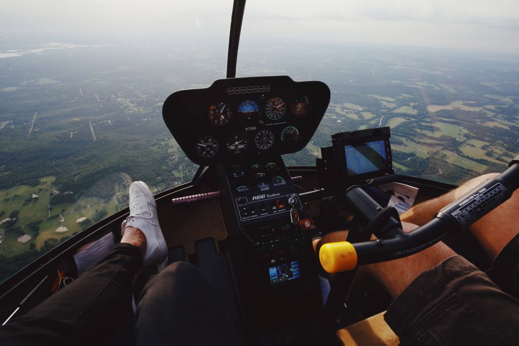 POV view from Robinson R66 helicopter cockpit flying over green countryside landscape wallpaper