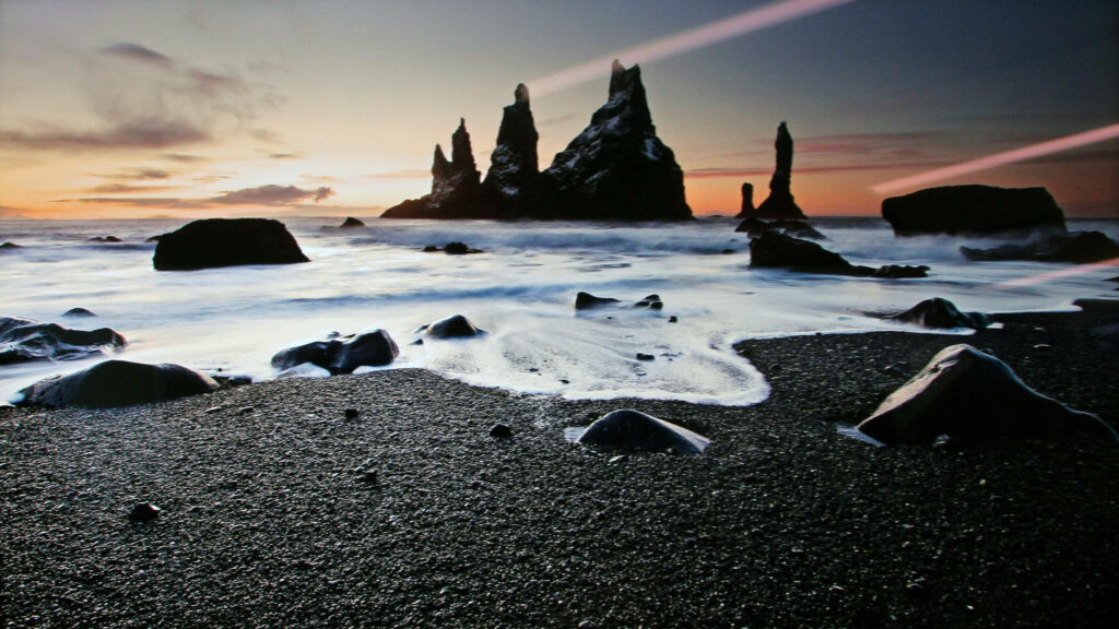 Sunset over Reynisfjara black sand beach with Reynisdrangar sea stacks and misty waves MacBook wallpaper