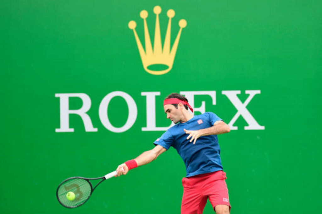 Roger Federer in Action on Tennis Court with Rolex Background Wallpaper