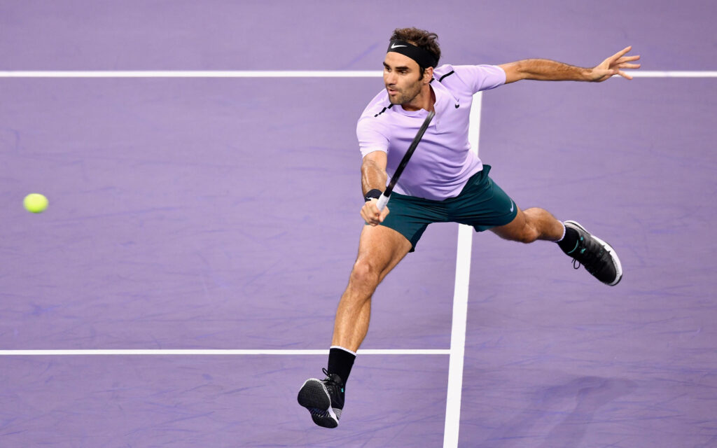 Roger Federer in Action: Purple Shirt on a Stunning Tennis Court Wallpaper