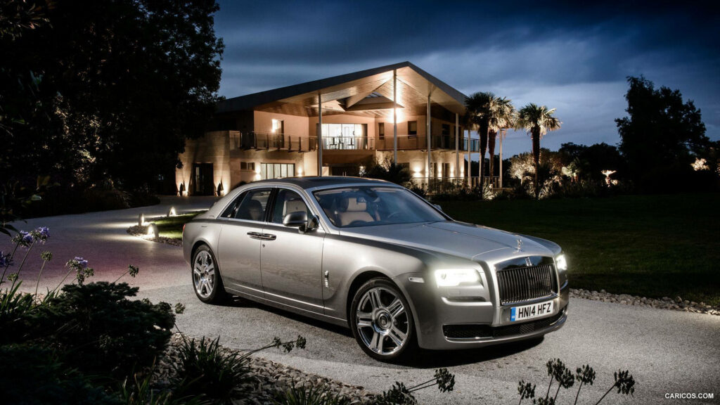 Rolling in Luxury: A Stunning View of the 2015 Rolls Royce Ghost in a Picturesque Garden Setting Wallpaper