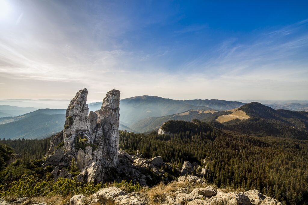 Romanian mountain landscape with rocky formations pine forests vibrant blue sky wallpaper background