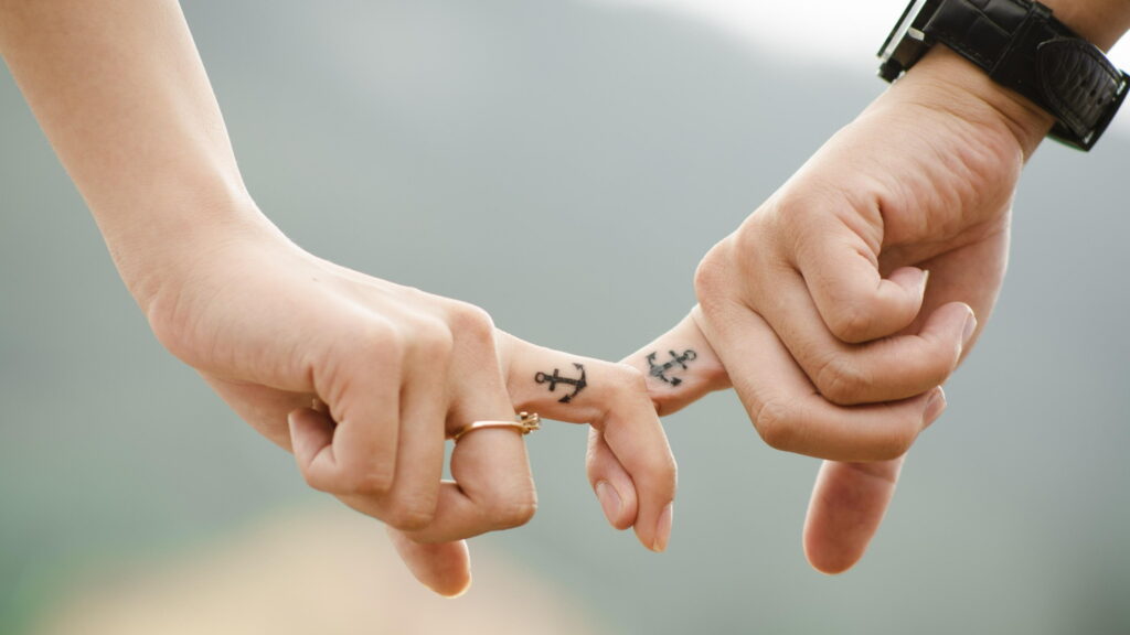 Romantic 4K wallpaper of couple’s pinky promise with anchor tattoos, gold ring, and watch