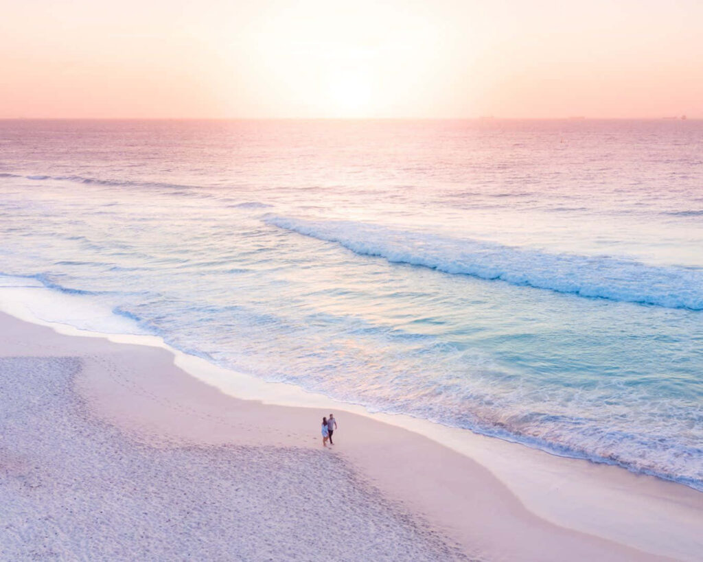 Romantic Sunset Beach Walk: Couple by Tranquil Ocean Waves Wallpaper