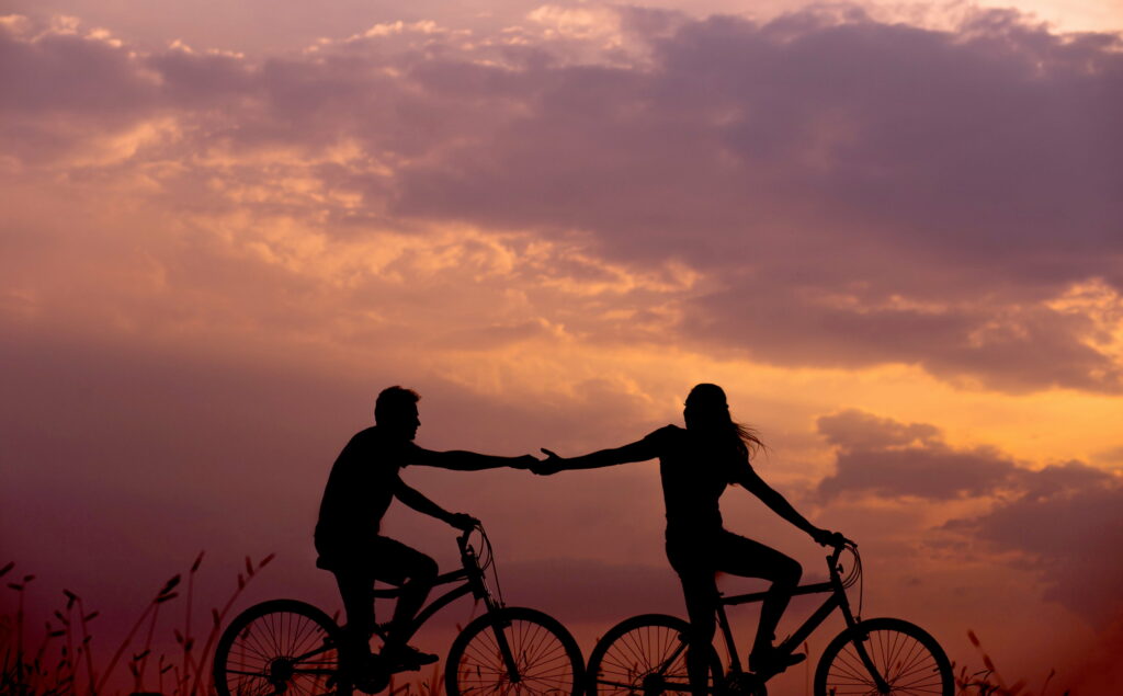 Silhouettes of Love: Capturing Romance in a Sunset Bike Ride Wallpaper