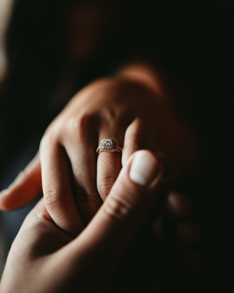 Close-up of couple’s hands with sparkling engagement ring romantic warm soft light wallpaper background