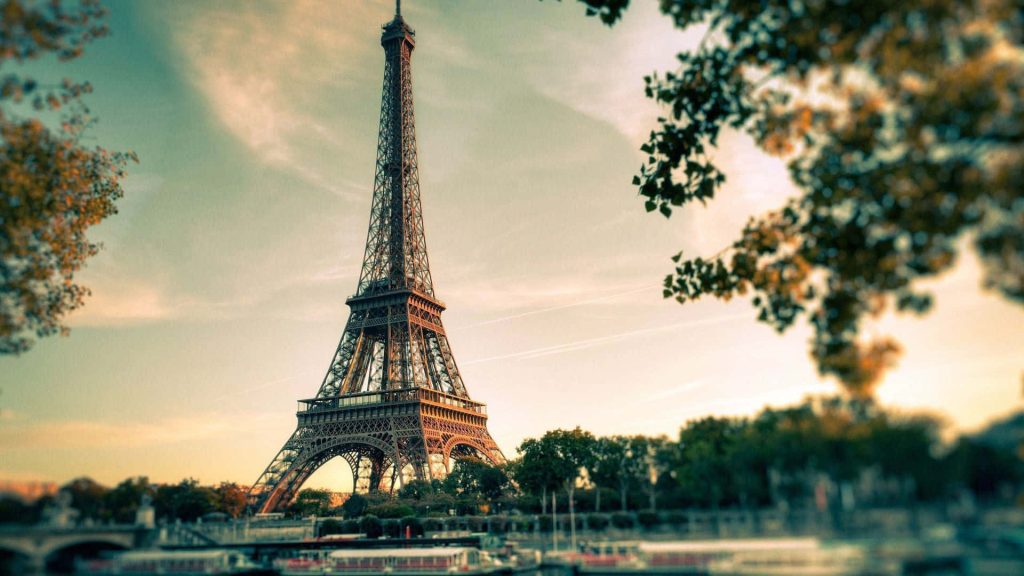 Eiffel Tower wallpaper at golden hour sunset with blurred foliage for romantic Paris desktop