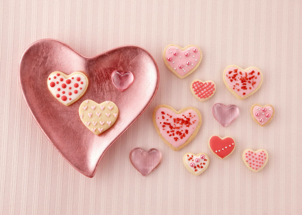 Heart-shaped cookies with pink red white icing on soft pink background romantic wallpaper