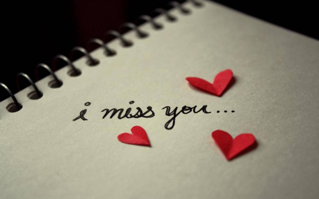 Handwritten i miss you message on spiral notebook with red paper hearts warm romantic mood Wallpaper