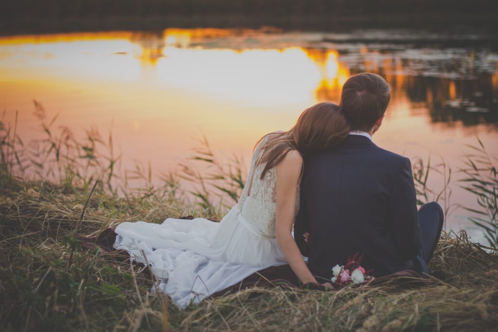 Romantic Lakeside Sunset Wallpaper: Newlyweds in Elegant Embrace