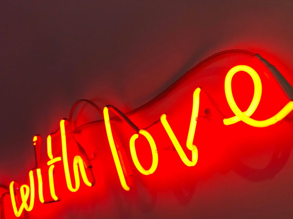 Vibrant neon with love script glowing yellow on soft red atmospheric background wallpaper