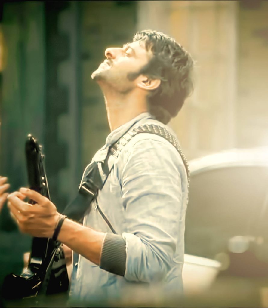 Prabhas in Darling movie wallpaper holding guitar soft golden lighting dreamy romantic charm