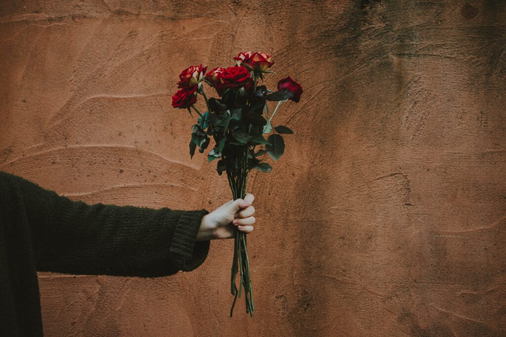 Romantic Red Roses Bouquet Against Rustic Brown Wall Background Wallpaper