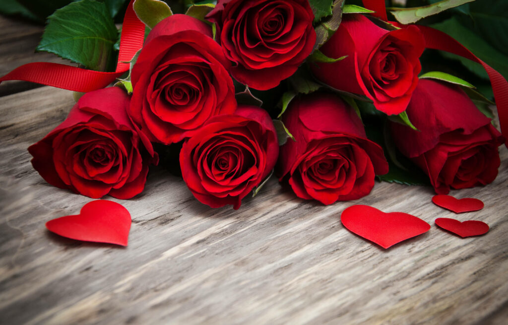 Romantic Red Roses Wallpaper: Elegant Floral Decor on Wooden Surface