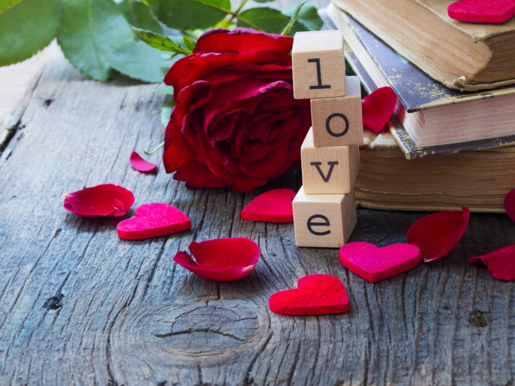Valentines Day wallpaper with LOVE wooden blocks red rose vintage books and red felt hearts