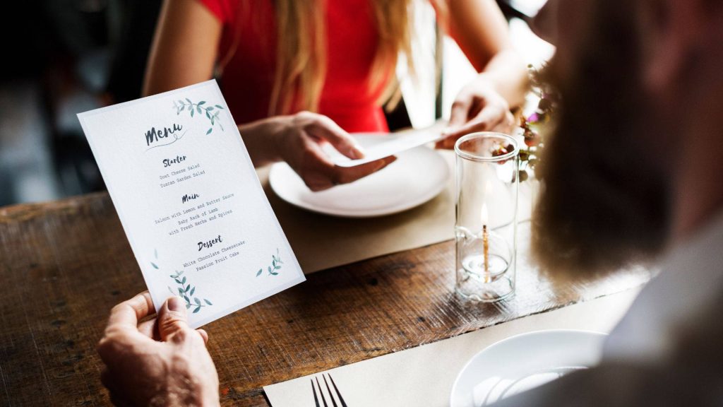 Romantic restaurant scene man holding menu cozy warm lighting rustic wooden table dinner wallpaper