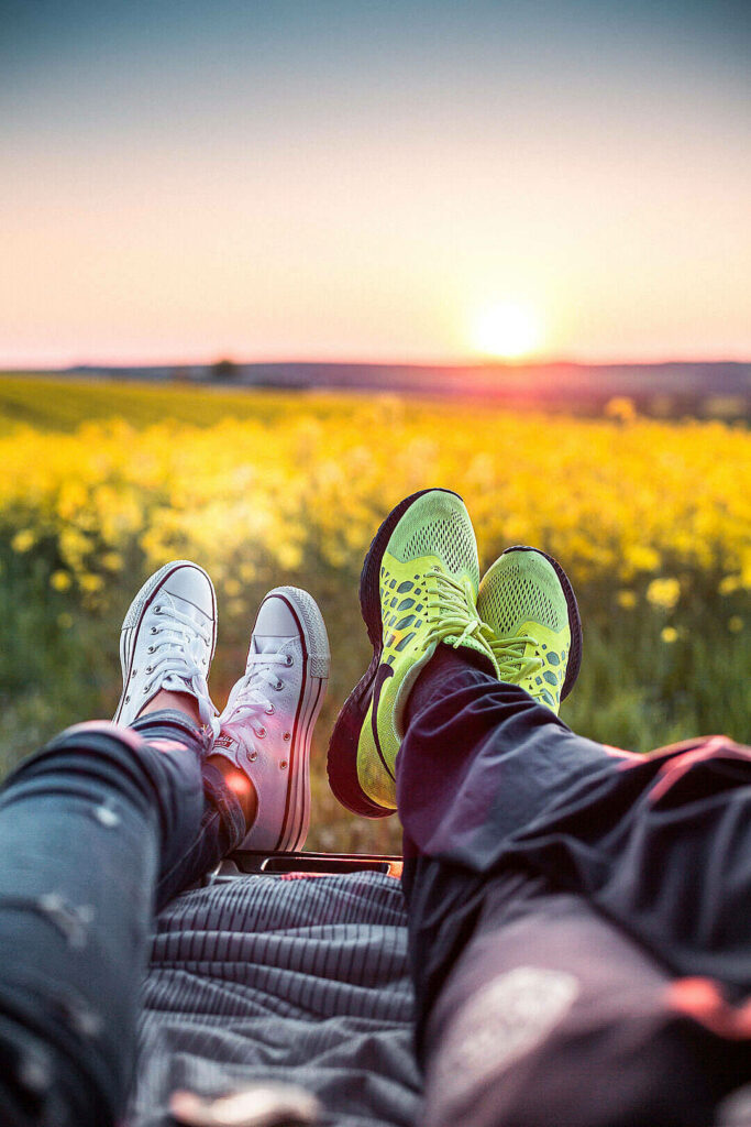 Sunset Romance: Couples' Cozy Trunk Date amidst Blooming Fields Wallpaper